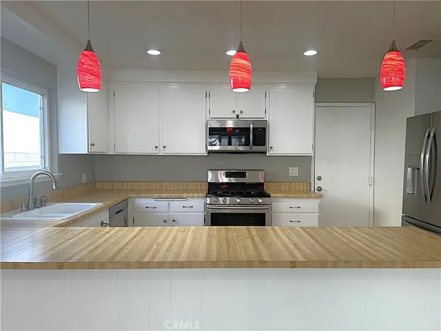 a kitchen that has a lot of cabinets and stainless steel appliances
