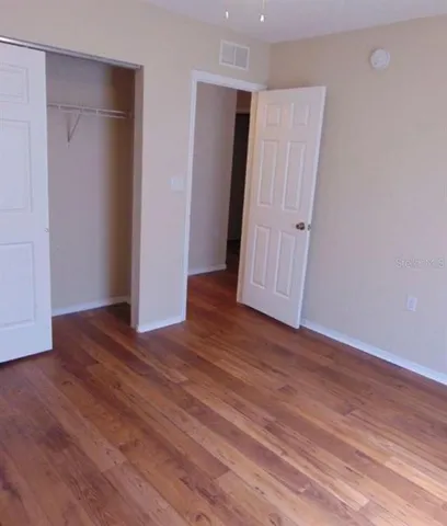 an empty room with wooden floor and closet
