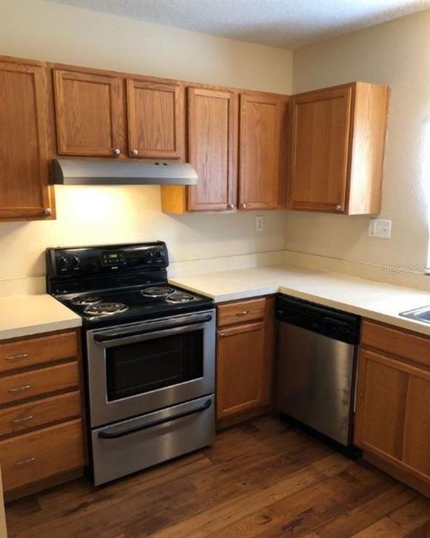 5816 Congress Street, Unit 102 New Port Richey, FL 34653 - Photo 2 of 14 a kitchen with granite countertop wooden cabinets and stainless steel appliances
