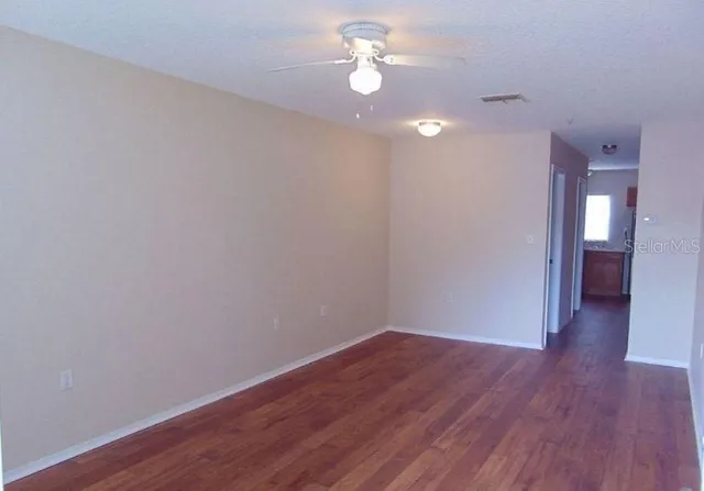 a view of a room with wooden floor and a ceiling fan