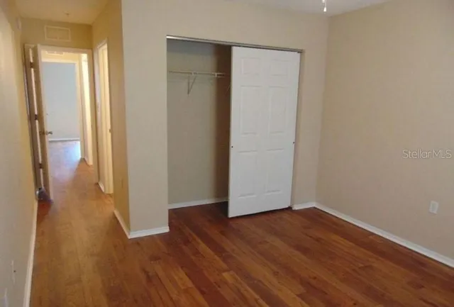an empty room with wooden floor and closet