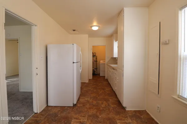 a view of a hallway with white walls and refrigerator