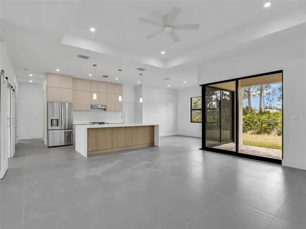 a view of an empty room with a window and kitchen view
