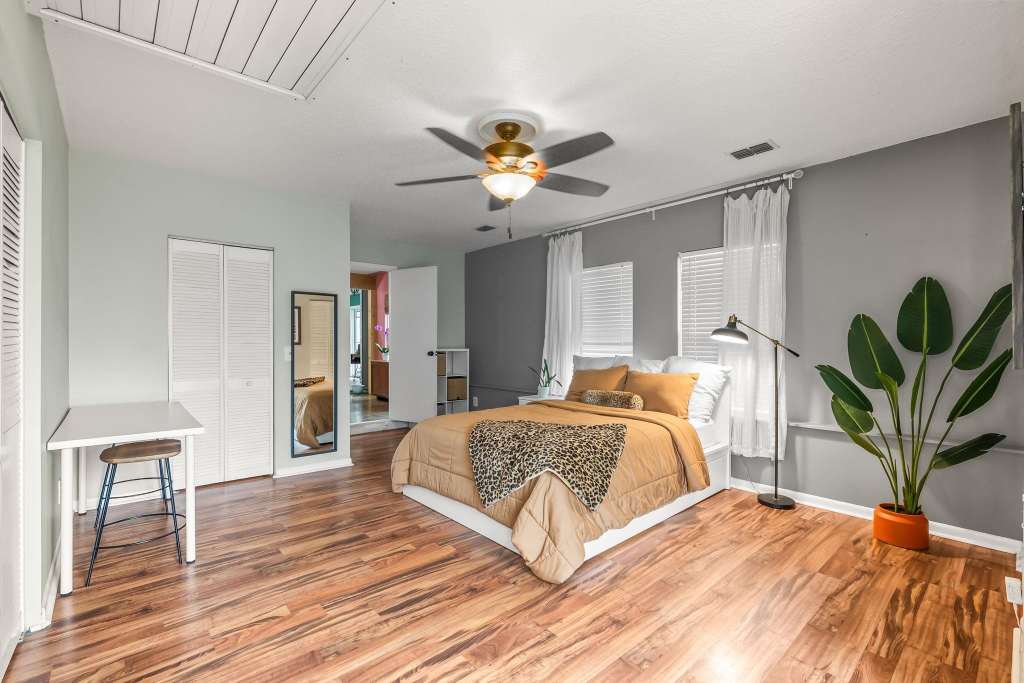 Bedroom with cooling unit, wood finished floors, a ceiling fan, and multiple closets