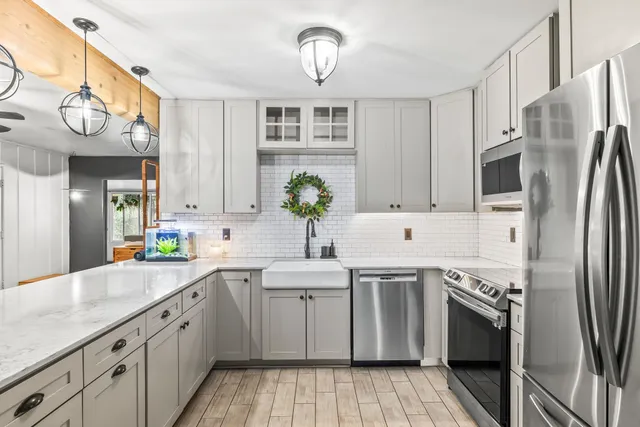 a kitchen with stainless steel appliances granite countertop a sink a stove a refrigerator cabinets and chairs