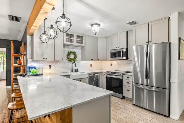 a kitchen with stainless steel appliances a large center island attached withe living room