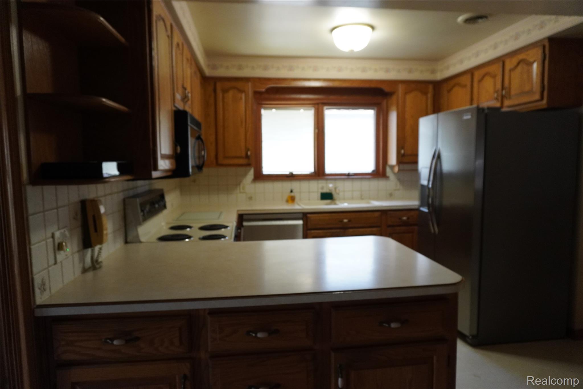 8115 Busch Street Center Line, MI 48015 - Photo 4 of 19 Kitchen featuring oak cabinetry, black refrigerator with ice dispenser, open shelves, white range with electric stovetop, and decorative backsplash