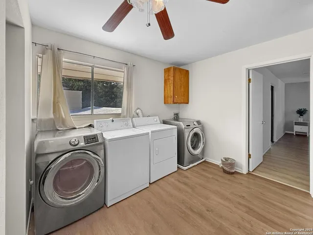 a view of a storage & utility room with wooden floor washing machine and a window