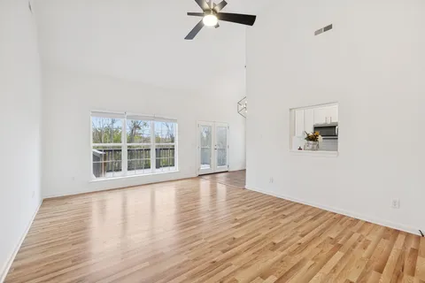 an empty room with wooden floor fan and windows