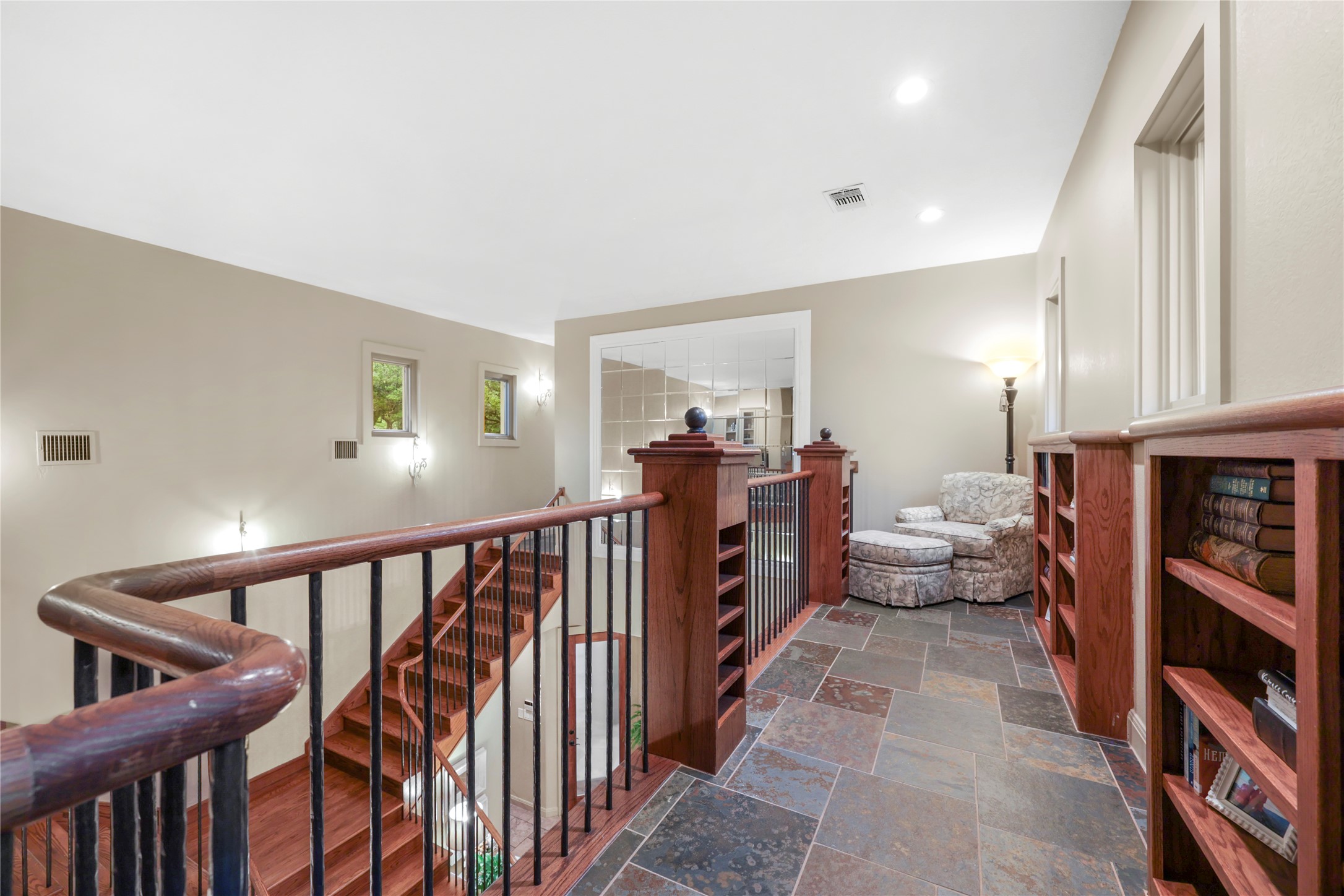 17501 Navigation Lane Lago Vista, TX 78645 - Photo 33 of 40 Spacious landing featuring natural stone tile flooring, built-in wooden bookcases, and a view of the wooden staircase with metal balusters