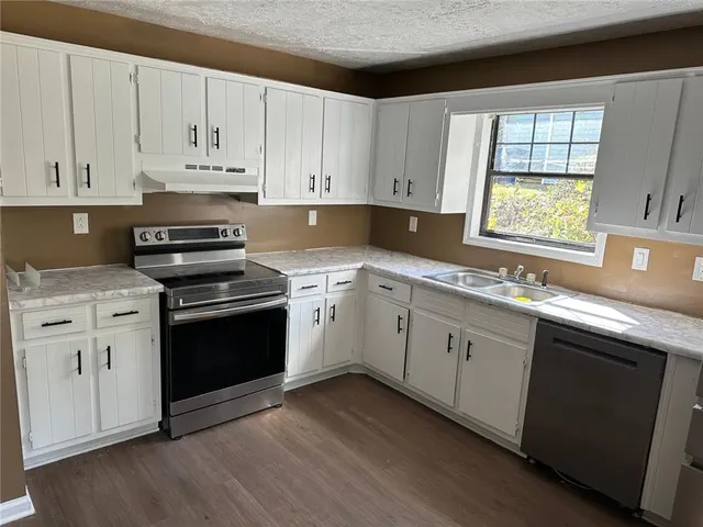 a kitchen with cabinets appliances a sink and a window
