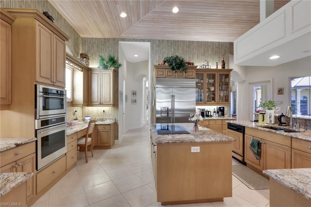 435 Terracina Way Naples, FL 34119 - Photo 17 of 50 a room with stainless steel appliances kitchen island granite countertop a table and chairs in it