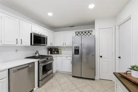 a kitchen with stainless steel appliances granite countertop a refrigerator stove a sink and white cabinets