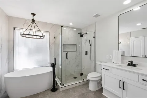 a bathroom with a granite countertop shower a toilet and a shower