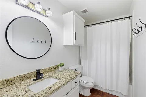 a bathroom with a granite countertop sink toilet and a mirror