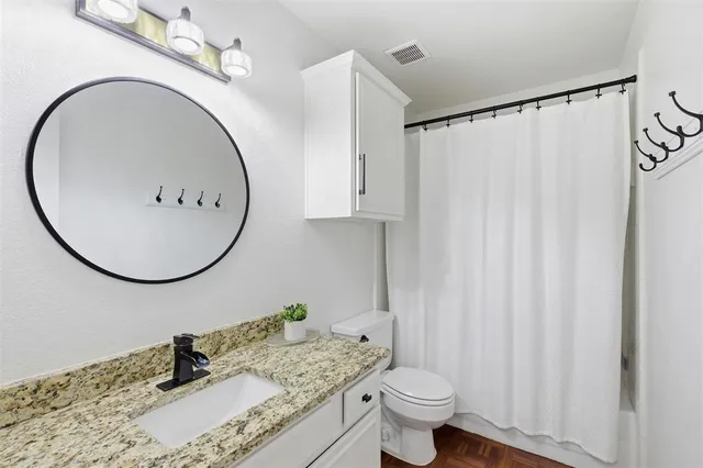 a bathroom with a granite countertop sink toilet and a mirror