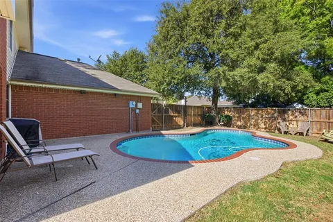 a view of a backyard with table and chairs potted plants and large tree