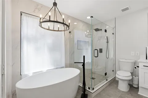 a bathroom with a white bath tub a toilet and a shower