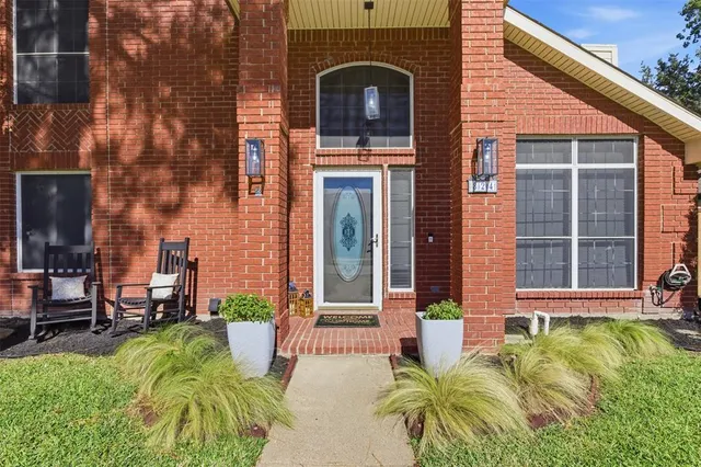 a view of a brick house with plants and large tree
