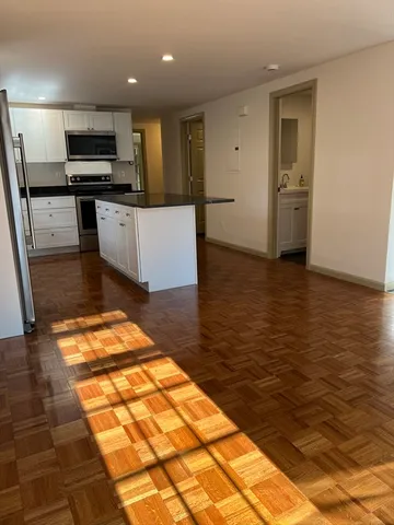 a view of kitchen with kitchen island granite countertop a stove and a sink