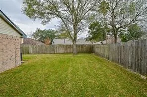 a view of a backyard with large trees and wooden fence