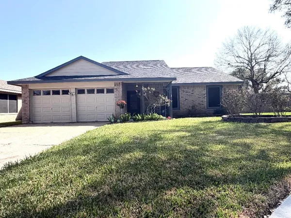 a front view of a house with yard and large tree