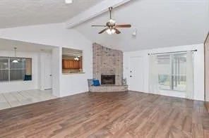 a view of an empty room with wooden floor fireplace and a window