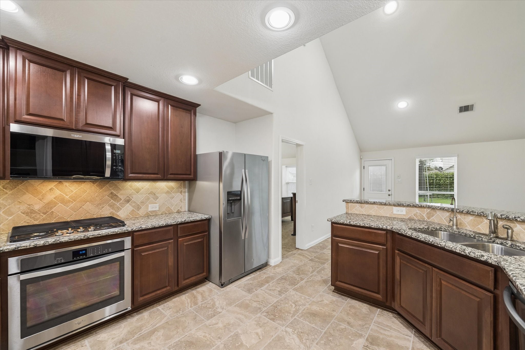 7015 Riata Hills Lane Spring, TX 77379 - Photo 13 of 33 This view highlights the seamless connection between the kitchen and the spacious breakfast area, showcasing the cohesive design of the countertops, modern stainless steel appliances, and an elegant backsplash, ready for the next owner to enjoy.