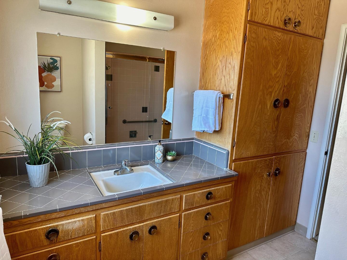 345 Green Valley Road Watsonville, CA 95076 - Photo 35 of 44 a bathroom with a granite countertop sink a mirror a vanity and shower