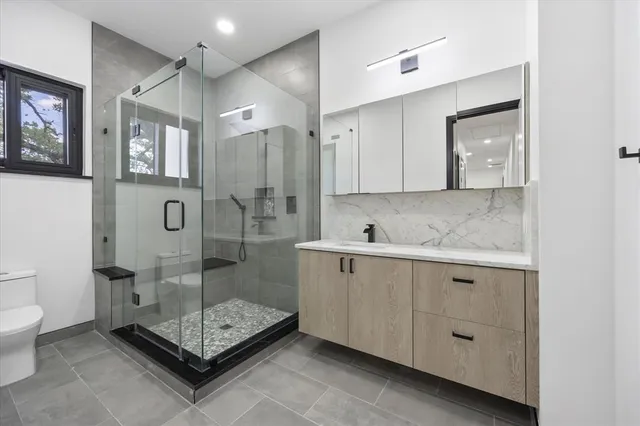 a bathroom with a shower sink mirror and toilet