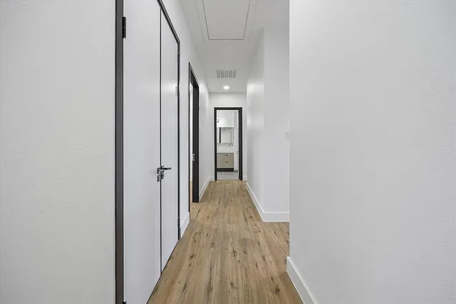a view of a hallway with wooden floor and a bathroom
