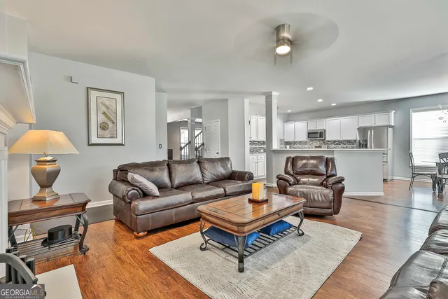 a kitchen with stainless steel appliances granite countertop a refrigerator a stove a sink dishwasher a dining table and chairs with wooden floor