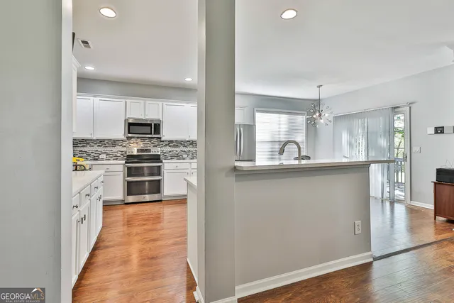 a kitchen with stainless steel appliances a sink cabinets and wooden floor