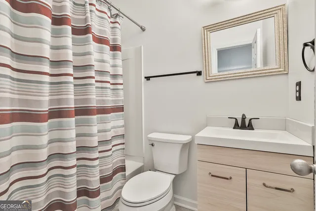 a bathroom with a toilet sink vanity and mirror