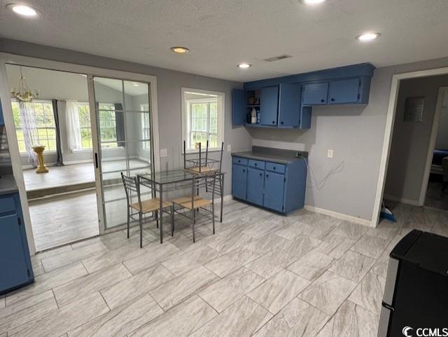 15 Mango Street Andrews, SC 29510 - Photo 24 of 26 Kitchen with blue cabinetry, recessed lighting, a textured ceiling, dark countertops, and refrigerator