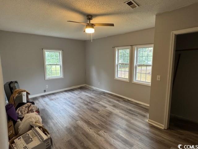 15 Mango Street Andrews, SC 29510 - Photo 25 of 26 Unfurnished bedroom featuring wood finished floors, a textured ceiling, ceiling fan, and a spacious closet