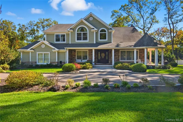 a front view of a house with a garden and lake view