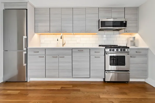 a kitchen with stainless steel appliances granite countertop a stove a sink and a microwave