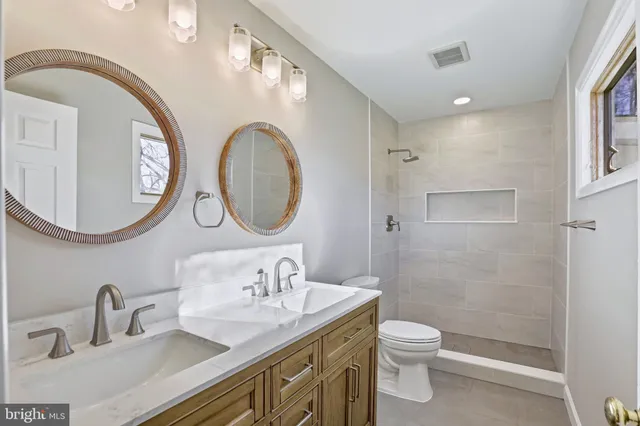 a bathroom with a granite countertop toilet a sink a mirror and a shower