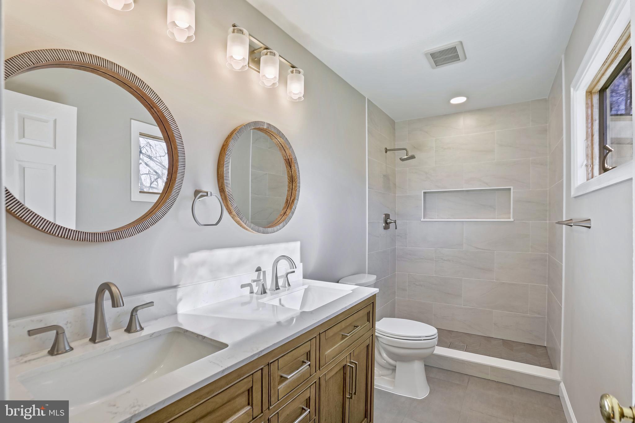 600 East Poplar Road Sterling, VA 20164 - Photo 14 of 32 a bathroom with a granite countertop toilet a sink a mirror and a shower