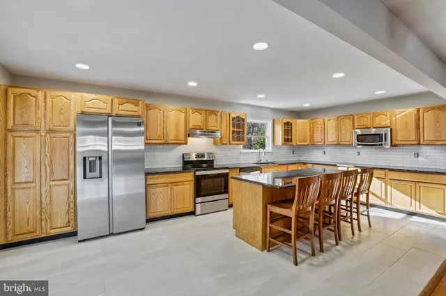 a kitchen with stainless steel appliances granite countertop a stove a sink a refrigerator and island