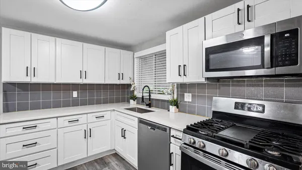 a kitchen with white cabinets a stove and a microwave
