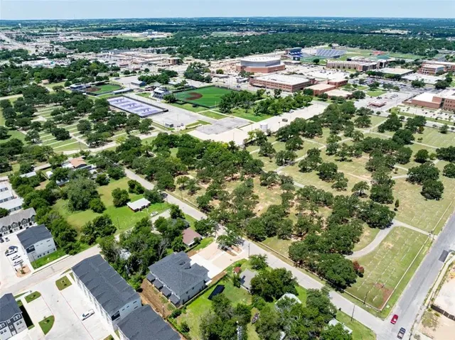 an aerial view of residential houses with outdoor space and trees
