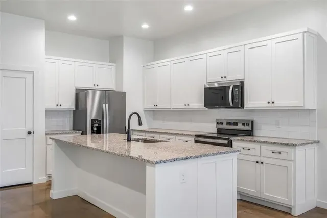 a kitchen with stainless steel appliances granite countertop a refrigerator sink and microwave