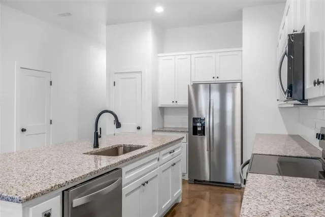 a kitchen with stainless steel appliances granite countertop a refrigerator and a sink