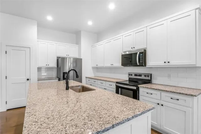 a kitchen with granite countertop a stove sink and microwave