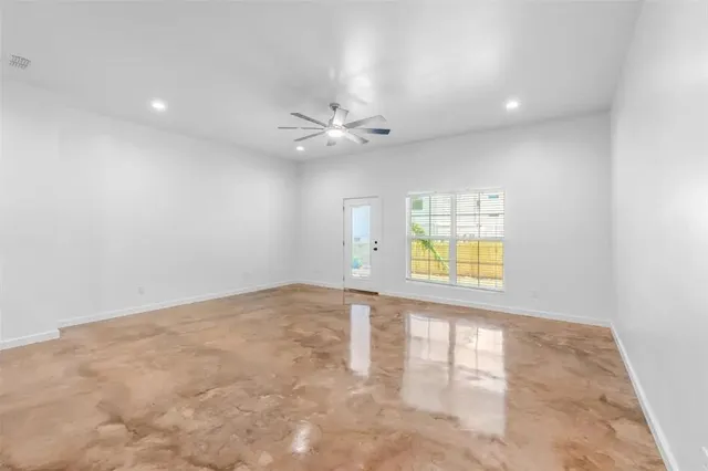 an empty room with windows and fan