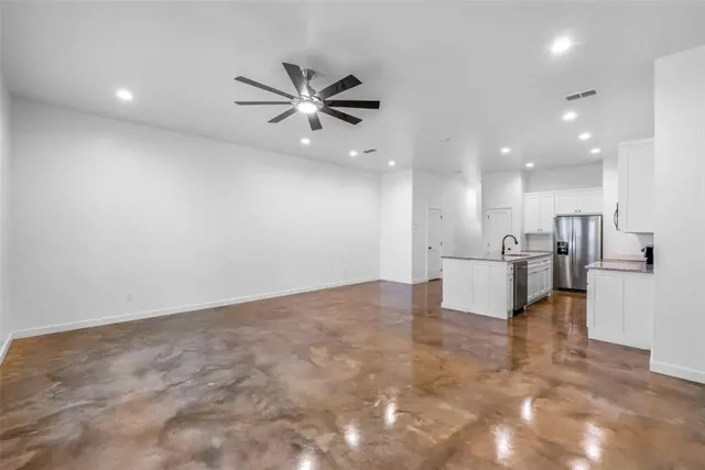 a view of an empty room and kitchen with sink