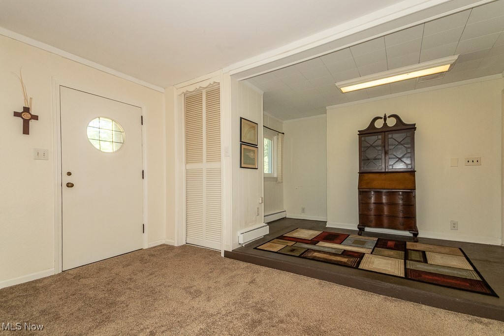 6533 Coleridge Road Painesville, OH 44077 - Photo 22 of 24 Foyer entrance with carpet floors, healthy amount of natural light, crown molding, and a baseboard heating unit