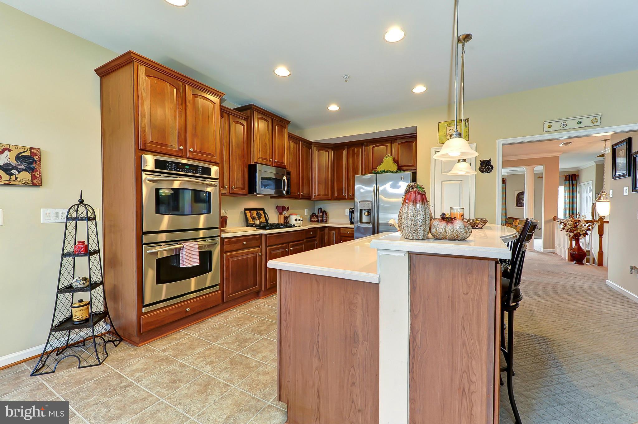 41888 Inspiration Terrace Aldie, VA 20105 - Photo 4 of 30 a kitchen with stainless steel appliances kitchen island granite countertop a refrigerator oven a sink dishwasher and white cabinets with wooden floor